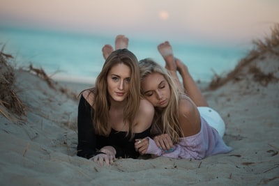 两个女人躺在沙滩上面对镜头
